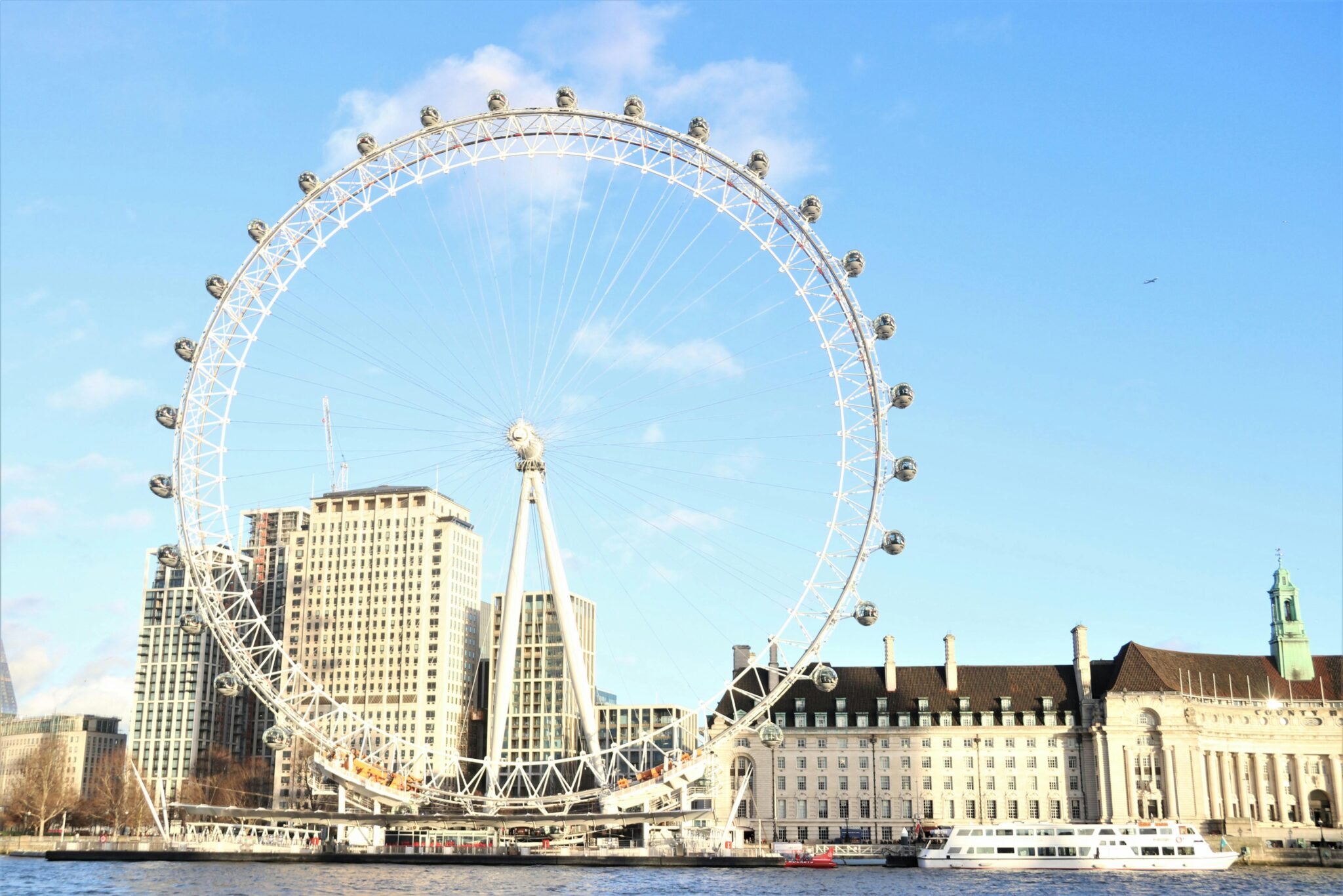 The London Eye ferris wheel captured on a sunny day with city buildings in the background.